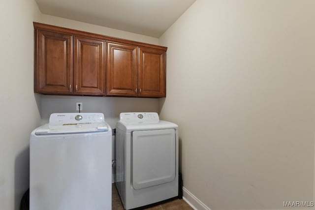 clothes washing area with cabinets, tile patterned flooring, and separate washer and dryer