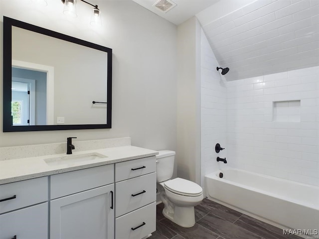 full bathroom featuring tiled shower / bath, vanity, and toilet