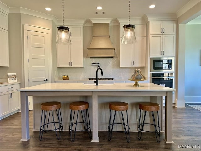 kitchen featuring dark wood-type flooring, a kitchen island with sink, and pendant lighting