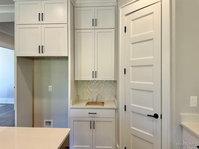 kitchen with decorative backsplash, wood-type flooring, light stone countertops, and white cabinets