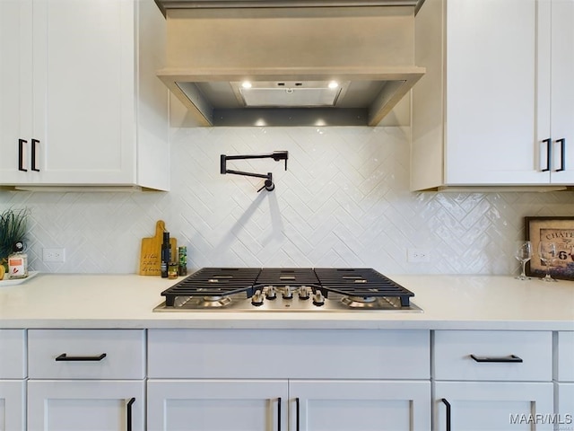 kitchen featuring tasteful backsplash, extractor fan, and white cabinetry