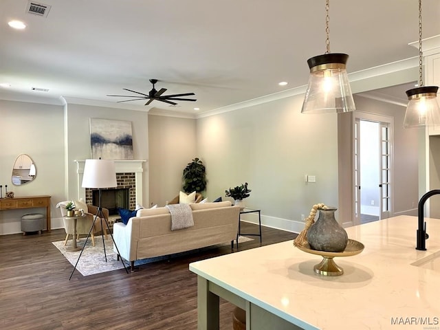 living room featuring dark hardwood / wood-style flooring, a brick fireplace, ornamental molding, and ceiling fan