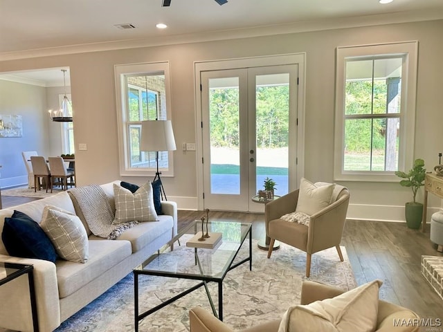 living room with crown molding, french doors, a healthy amount of sunlight, and light wood-type flooring