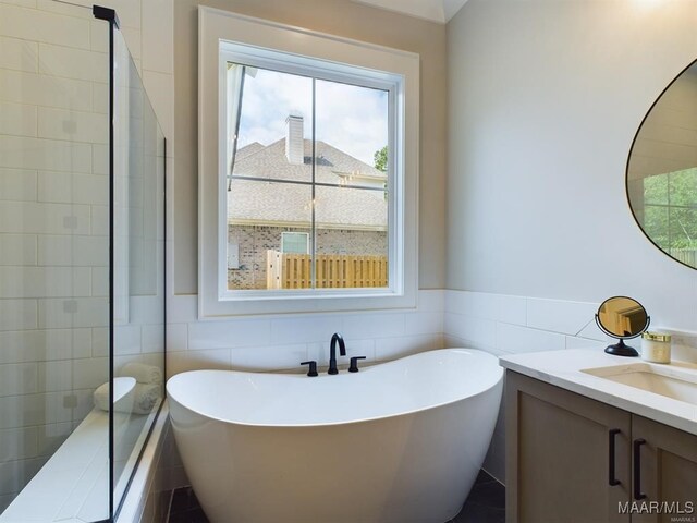 bathroom with vanity, a tub, and tile walls