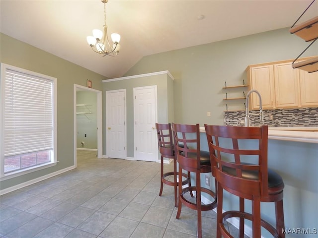 dining room featuring sink, light tile patterned floors, lofted ceiling, and an inviting chandelier