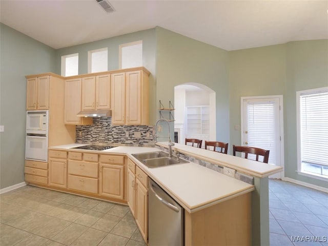 kitchen featuring stainless steel dishwasher, light brown cabinets, kitchen peninsula, and sink