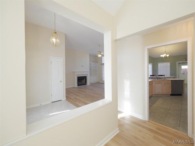 hall with sink, a chandelier, vaulted ceiling, and light hardwood / wood-style flooring