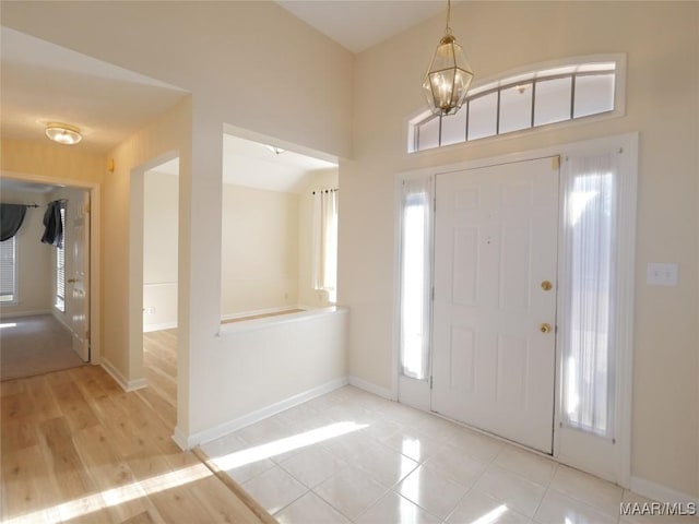 entryway with light tile patterned flooring and an inviting chandelier