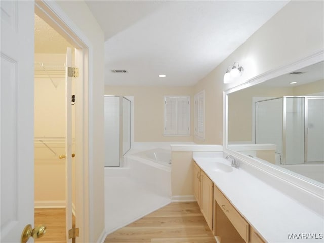 bathroom featuring wood-type flooring, vanity, and shower with separate bathtub