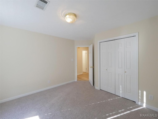 unfurnished bedroom featuring light colored carpet and a closet