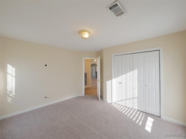 unfurnished bedroom featuring light colored carpet and a closet