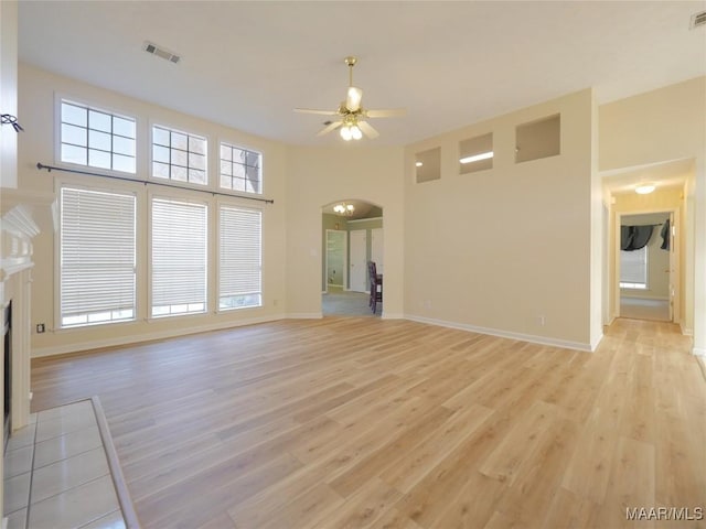 unfurnished living room featuring ceiling fan, a towering ceiling, and light hardwood / wood-style flooring