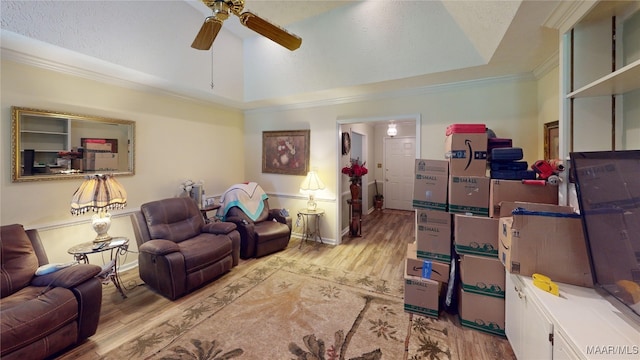 living room with ceiling fan, crown molding, light hardwood / wood-style floors, a textured ceiling, and a tray ceiling