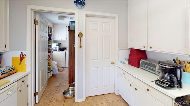 kitchen featuring stove, white dishwasher, washing machine and clothes dryer, white cabinetry, and light tile patterned flooring