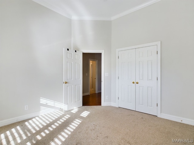 unfurnished bedroom featuring carpet flooring, ornamental molding, a high ceiling, and a closet