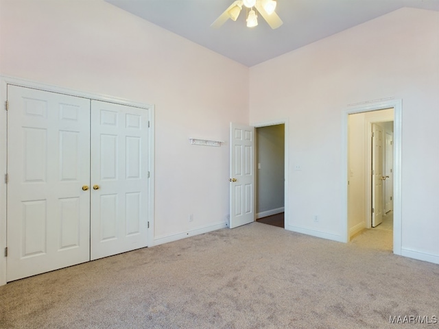 unfurnished bedroom with ceiling fan, a closet, light colored carpet, and lofted ceiling