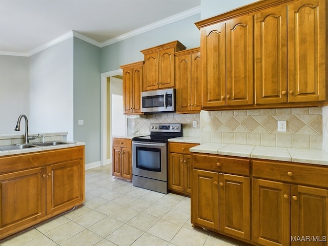 kitchen with sink, crown molding, decorative backsplash, light tile patterned flooring, and appliances with stainless steel finishes