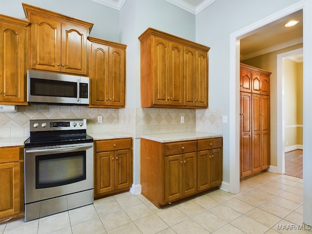 kitchen with tasteful backsplash, crown molding, light tile patterned flooring, and appliances with stainless steel finishes