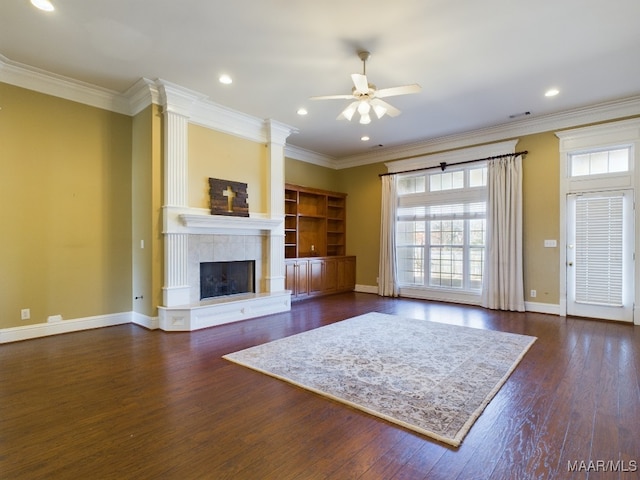 unfurnished living room featuring crown molding, a fireplace, ceiling fan, and dark wood-type flooring