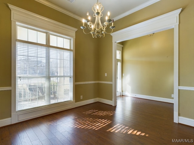 spare room with a healthy amount of sunlight, dark hardwood / wood-style floors, ornamental molding, and a notable chandelier