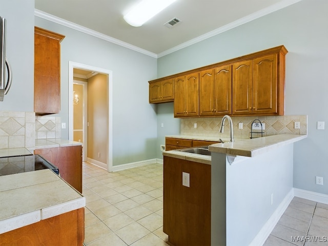 kitchen featuring backsplash, kitchen peninsula, crown molding, and light tile patterned floors