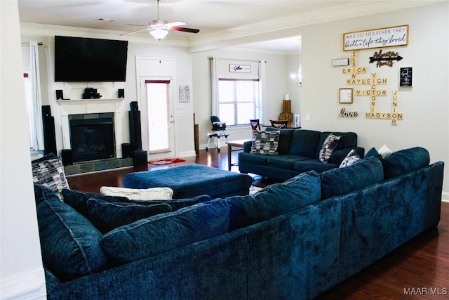 living room featuring a fireplace, ceiling fan, crown molding, and dark wood-type flooring