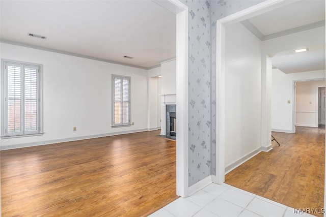 unfurnished living room featuring a tile fireplace, light hardwood / wood-style flooring, and crown molding