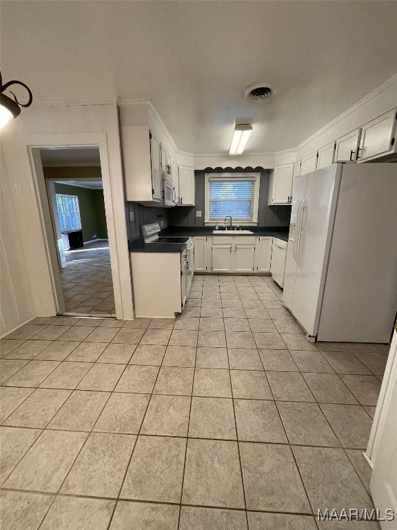 kitchen with white cabinetry, white appliances, and light tile patterned floors