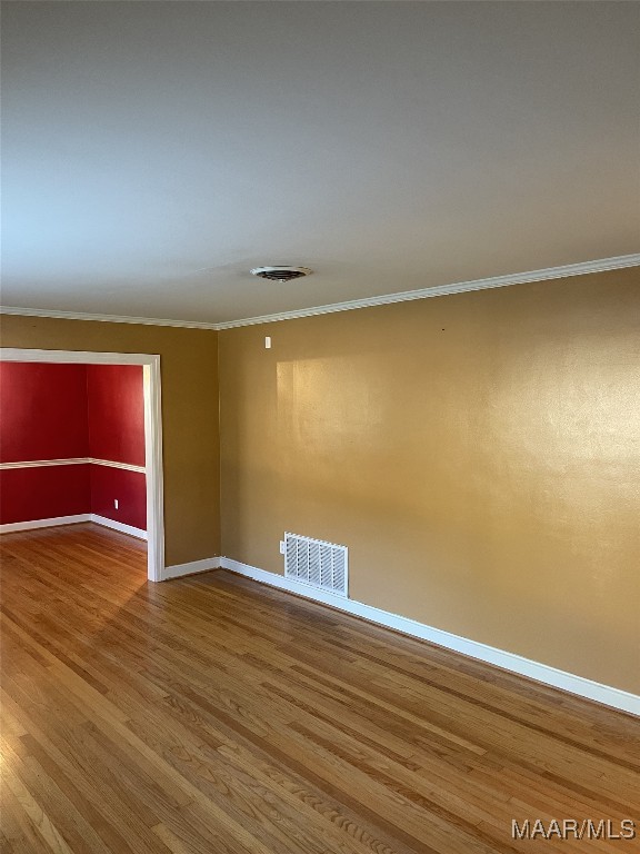 empty room with crown molding and hardwood / wood-style floors