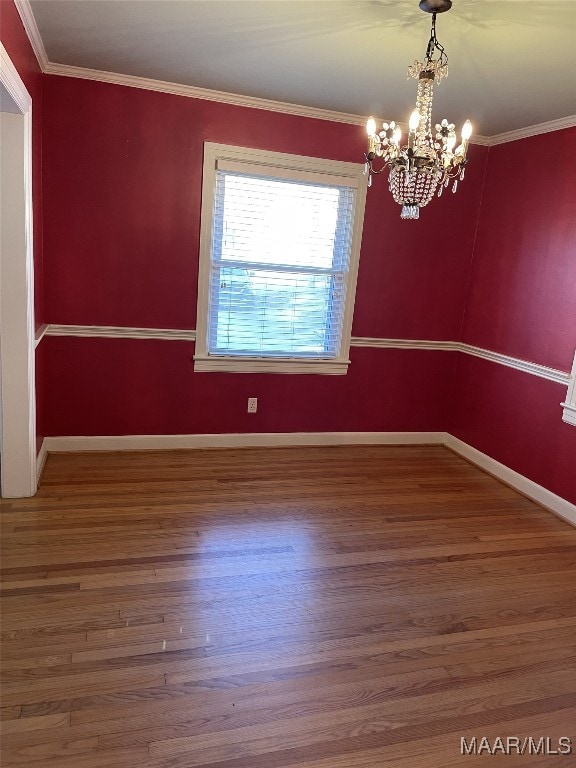 unfurnished room featuring hardwood / wood-style floors, an inviting chandelier, and crown molding