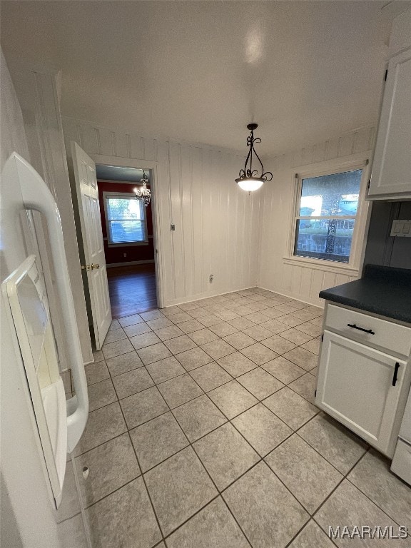 unfurnished dining area with light tile patterned floors and an inviting chandelier