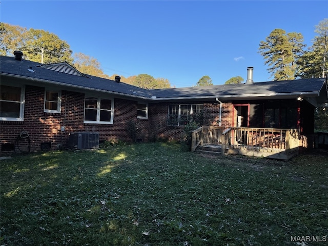 rear view of house featuring central AC and a lawn