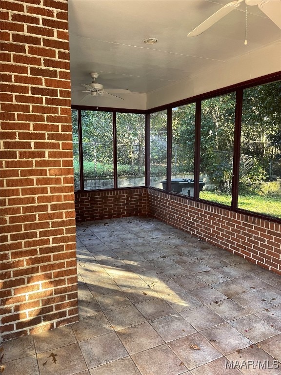 unfurnished sunroom featuring ceiling fan and a wealth of natural light