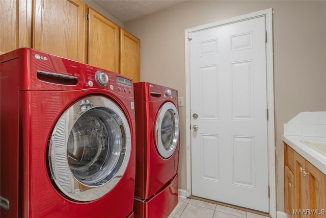 washroom featuring cabinets, light tile patterned floors, washing machine and dryer, and a textured ceiling