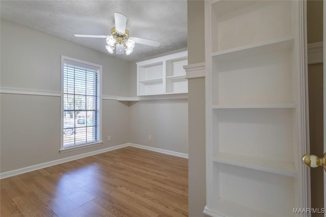 spacious closet with light hardwood / wood-style floors and ceiling fan