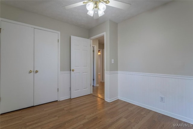 unfurnished bedroom with hardwood / wood-style flooring, ceiling fan, a textured ceiling, and a closet