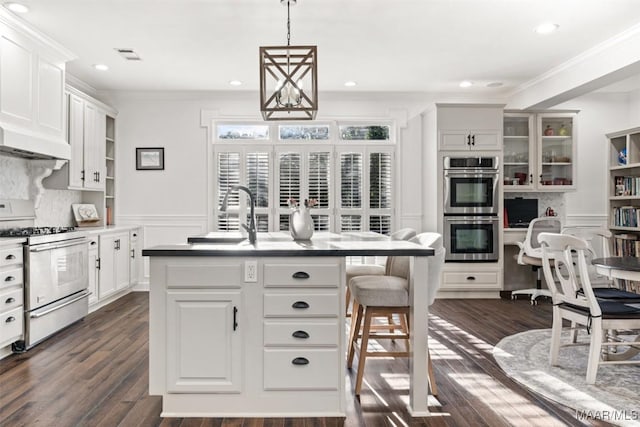 kitchen with white cabinets, appliances with stainless steel finishes, and a center island with sink