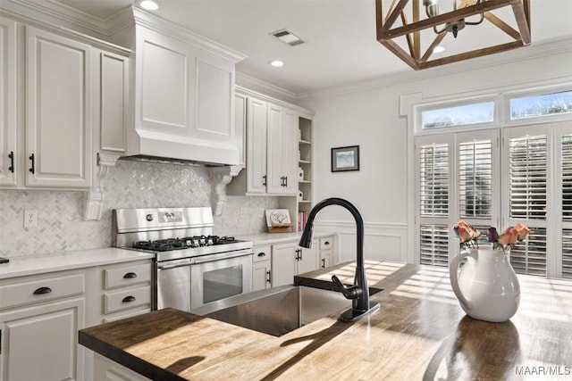 kitchen featuring stainless steel gas range oven, crown molding, white cabinetry, and sink