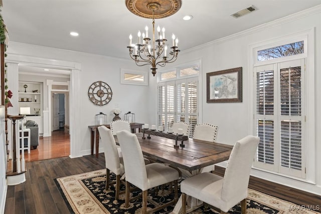 dining area featuring crown molding, built in features, dark wood-type flooring, and an inviting chandelier