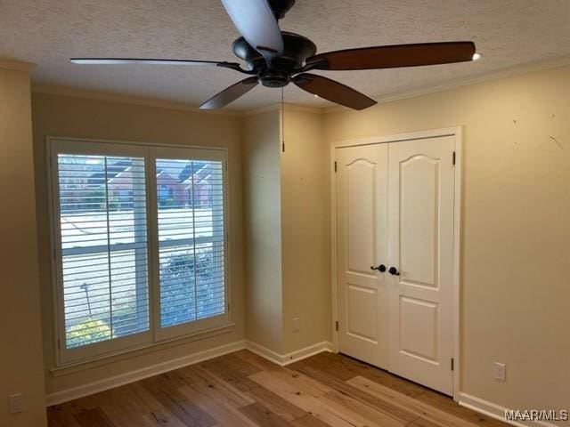 empty room featuring a textured ceiling, ceiling fan, light hardwood / wood-style floors, and crown molding