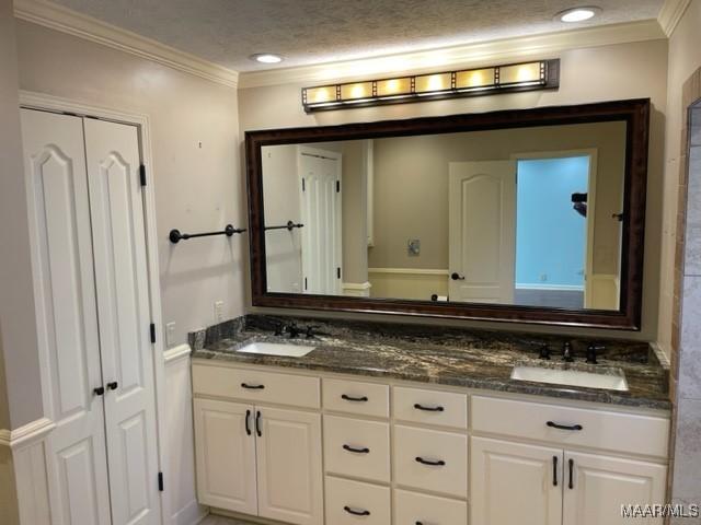 bathroom with crown molding, vanity, and a textured ceiling