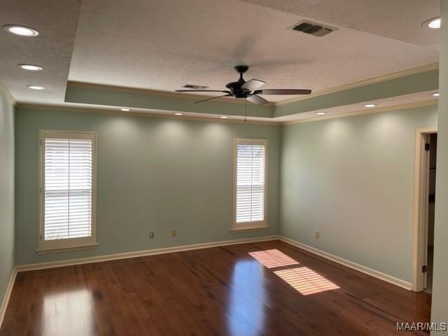 unfurnished room featuring a tray ceiling, dark hardwood / wood-style floors, ornamental molding, and ceiling fan