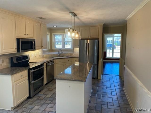 kitchen featuring decorative backsplash, stainless steel appliances, sink, a center island, and hanging light fixtures