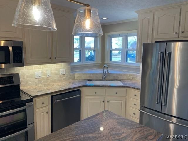 kitchen featuring white cabinets, sink, ornamental molding, appliances with stainless steel finishes, and decorative light fixtures