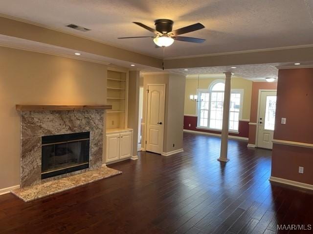 unfurnished living room featuring built in shelves, ceiling fan, dark wood-type flooring, a fireplace, and ornamental molding