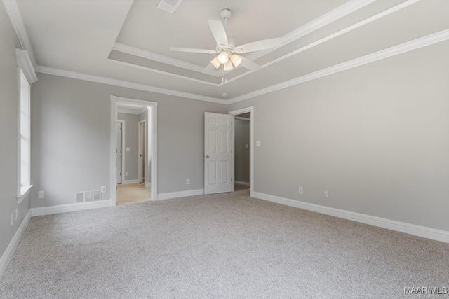 carpeted empty room featuring a tray ceiling, ceiling fan, and crown molding