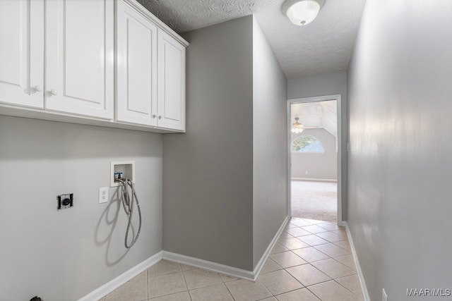 washroom with cabinets, hookup for a washing machine, light tile patterned floors, a textured ceiling, and hookup for an electric dryer