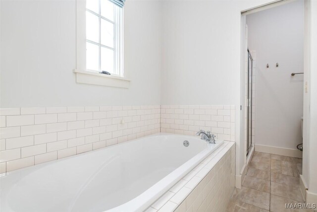 bathroom featuring tile patterned flooring and tiled bath