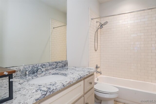 full bathroom featuring vanity, tiled shower / bath combo, and toilet