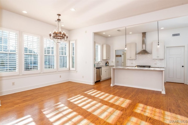 kitchen with white cabinets, wall chimney exhaust hood, and pendant lighting